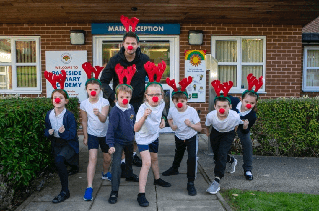 group of children wearing red antler headbands and red noses ready to set off for a run