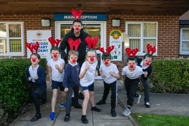 group of children wearing red antler headbands and red noses ready to set off for a run