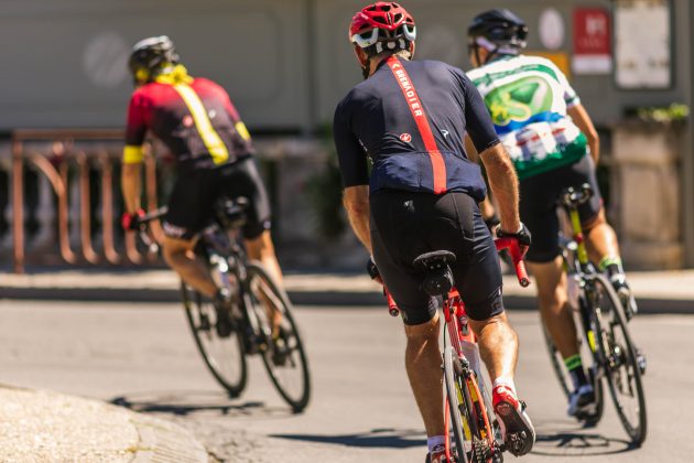 three cyclists on racing bikes, seen from rear
