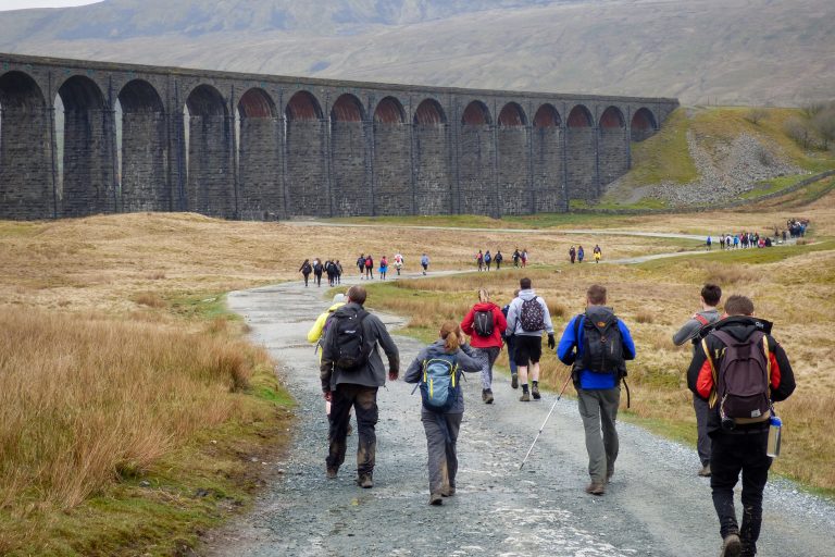 Walkers on footpath with viaduct in the background