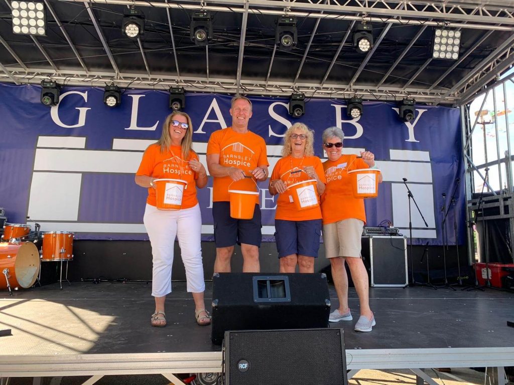 4 people in orange hospice t-shorts with collection buckets