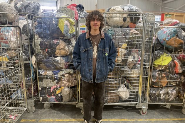 young man standing in front of bags of donated clothing