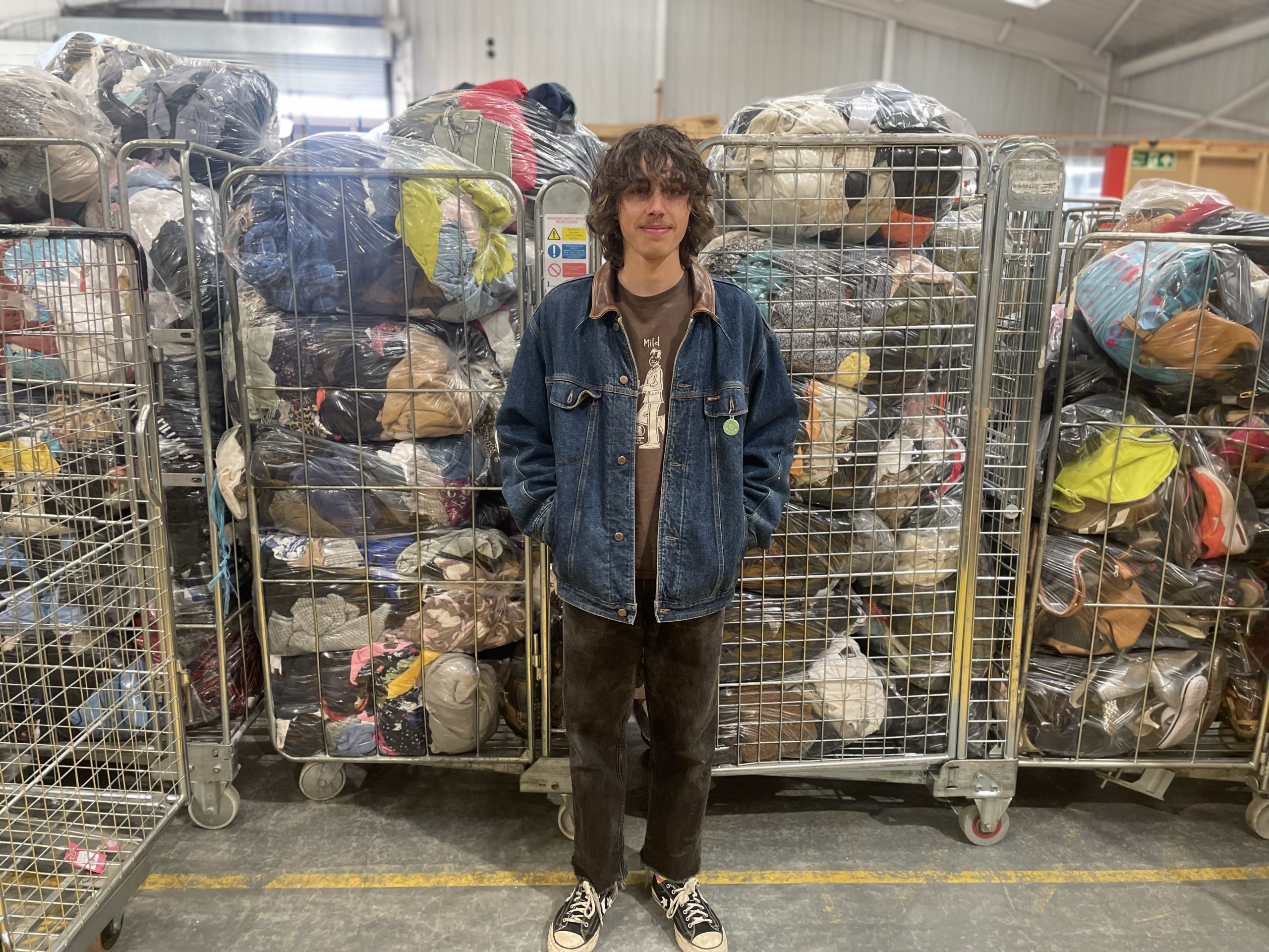 young man standing in front of bags of donated clothing