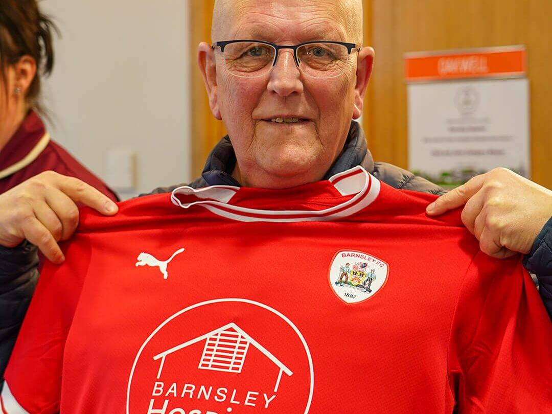 Man holding a Barnsley FC Hospice shirt up