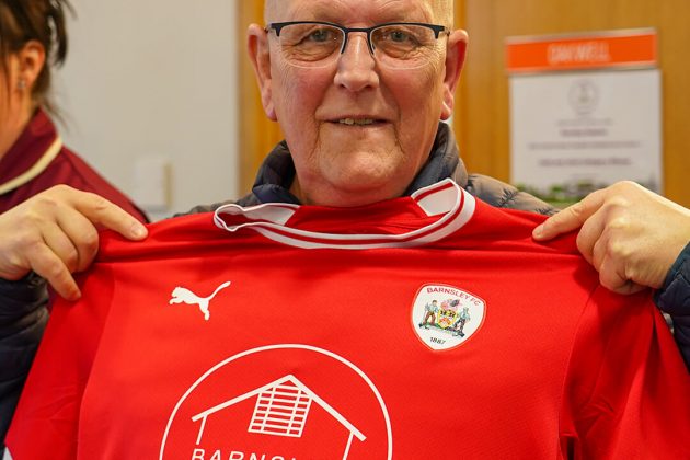 Man holding a Barnsley FC Hospice shirt up