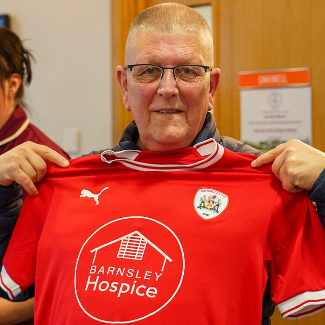 Man holding a Barnsley FC Hospice shirt up