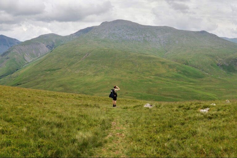 walker on grassy footpath with hills in background